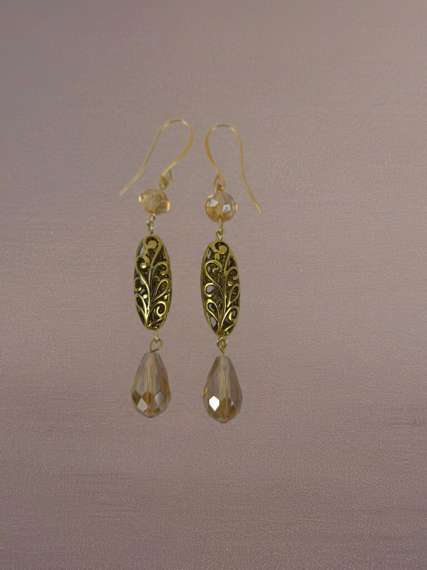 Gold earrings with teardrop-shaped drops on a brown background