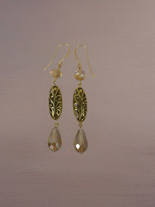 Gold earrings with teardrop-shaped drops on a brown background