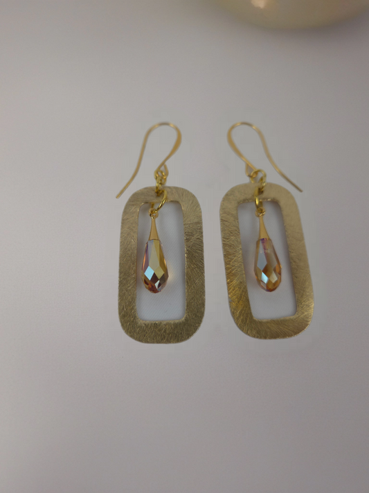 Gold earrings with teardrop-shaped stones on a light gray background