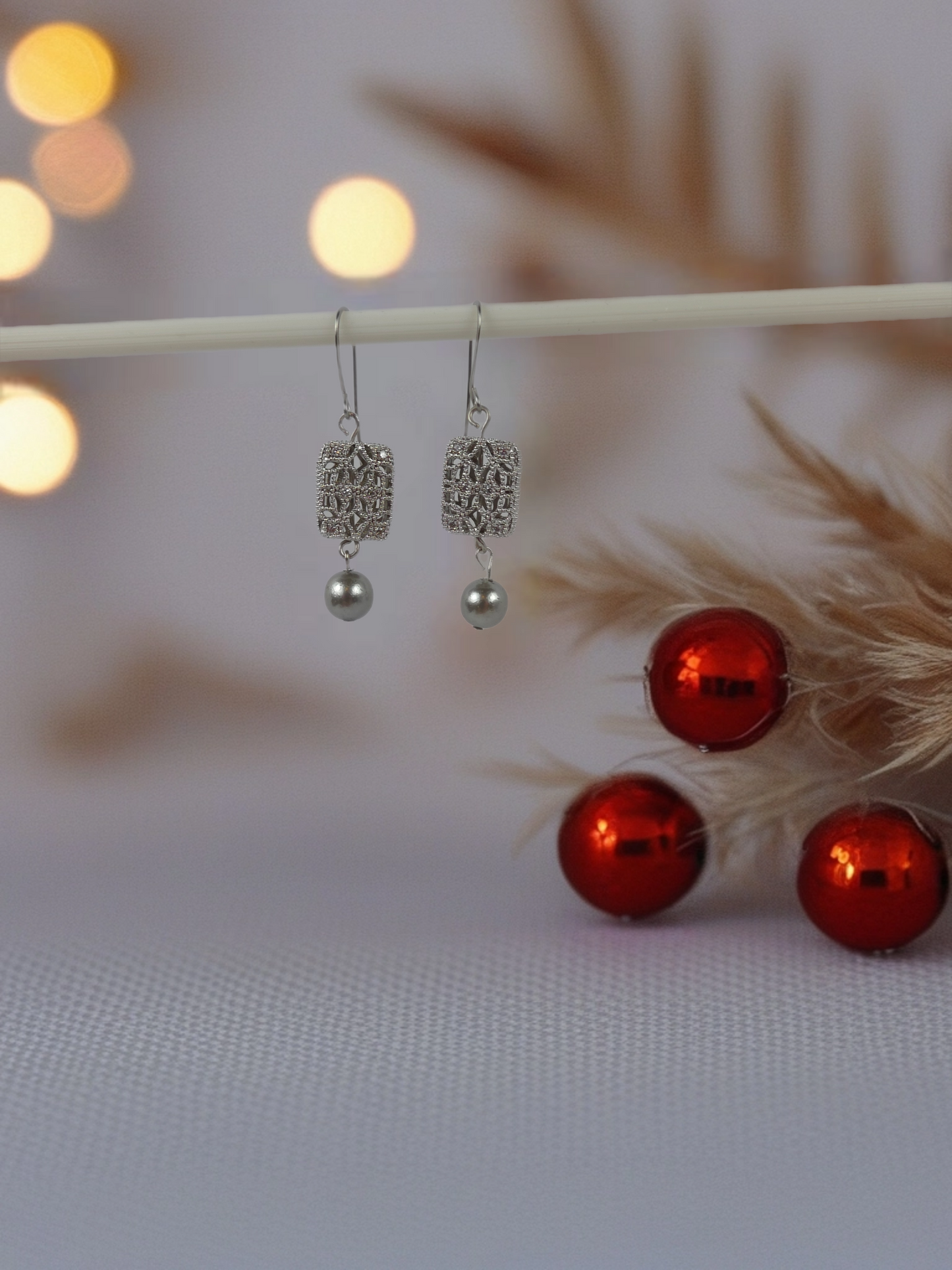 Silver earrings with red beads on a blurred background