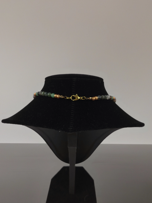 Necklace on a black velvet stand against a plain background