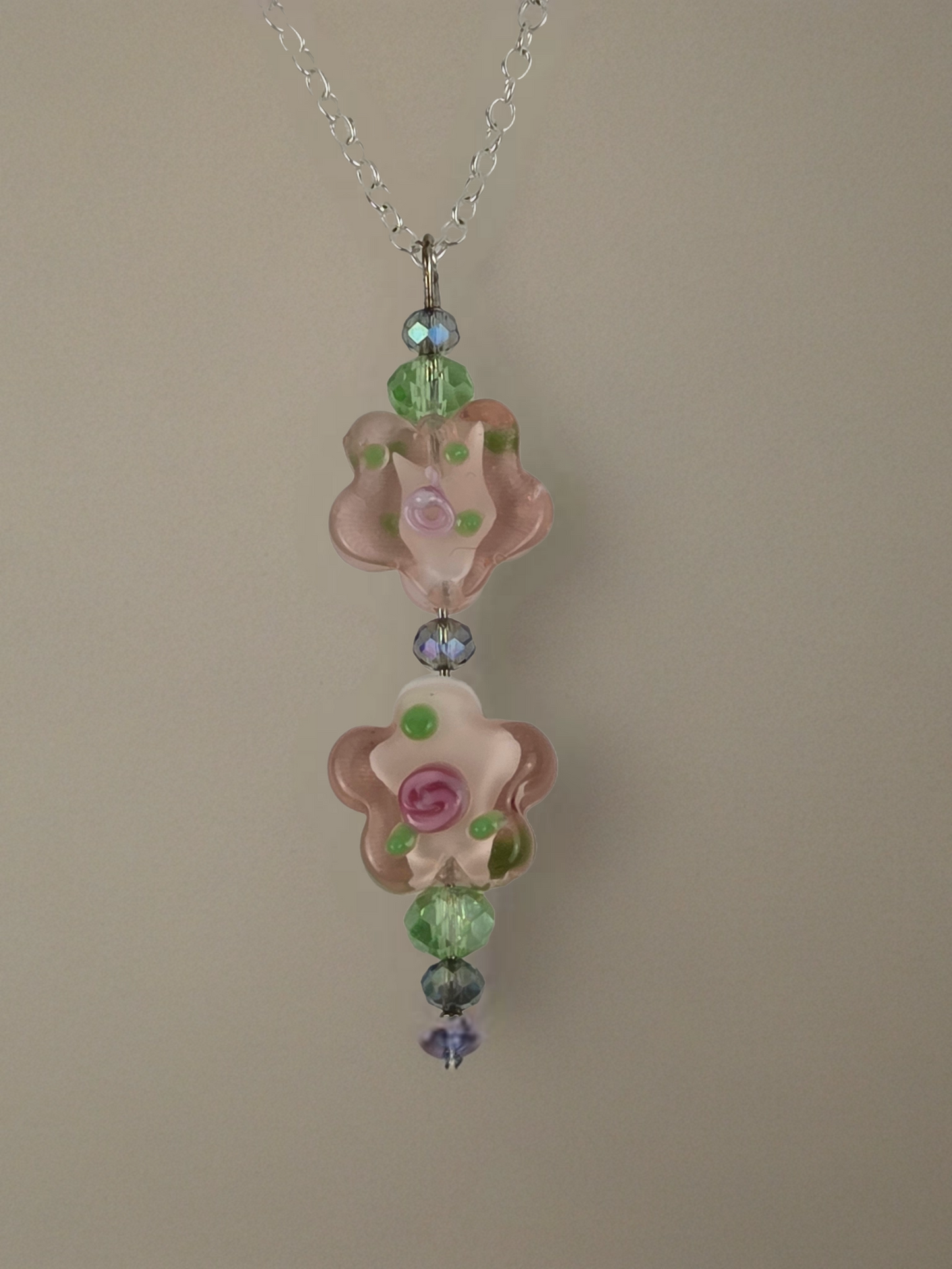 Necklace with floral pendant and multicolored beads on a beige background