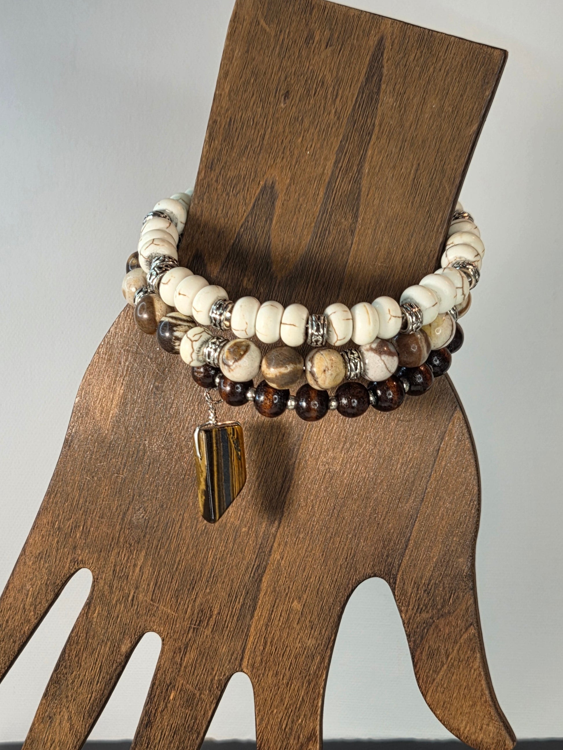 Wooden hand holding a beaded bracelet on a white background