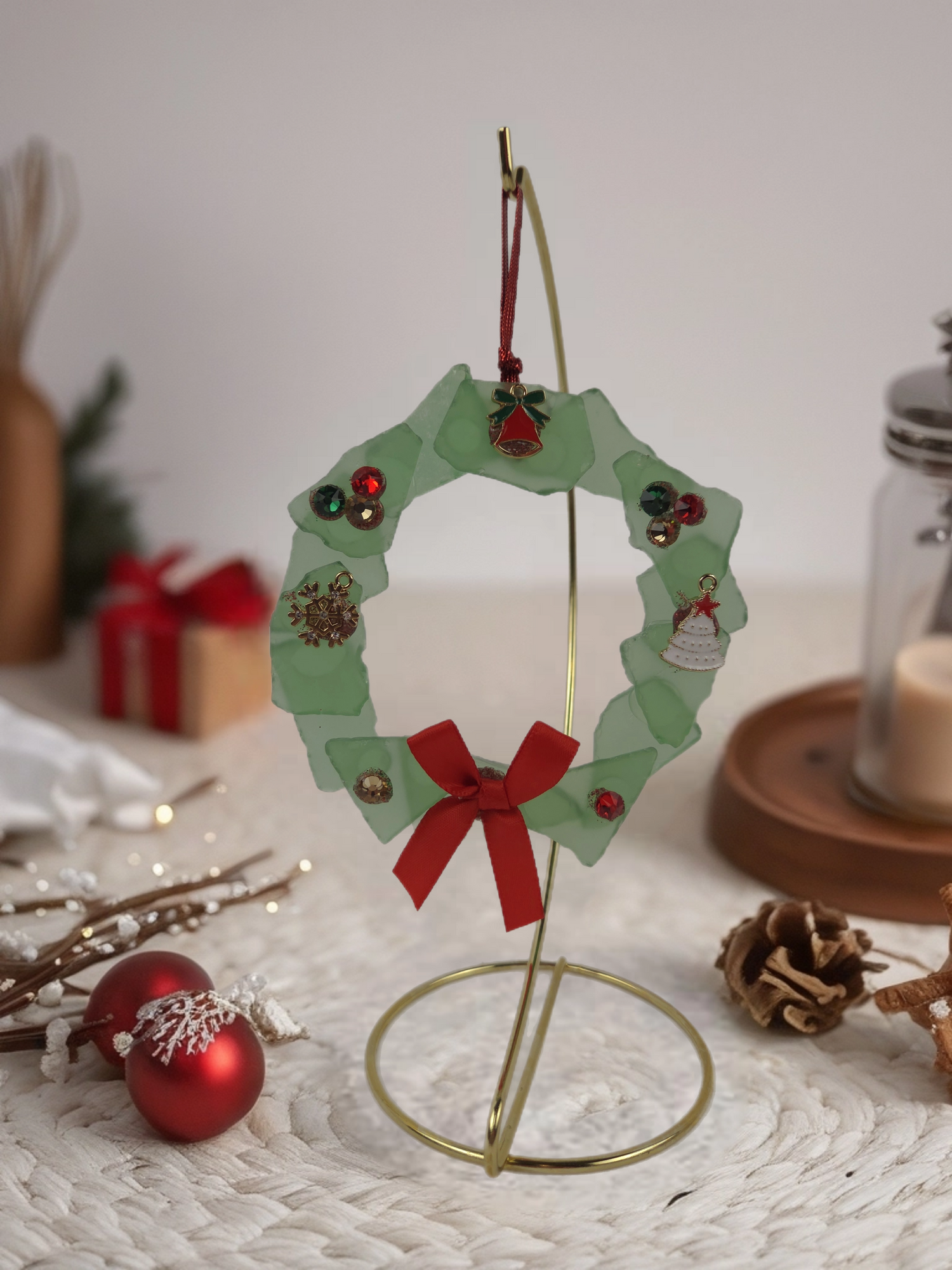 Decorative Christmas wreath ornament on a stand with red bow and small ornaments.