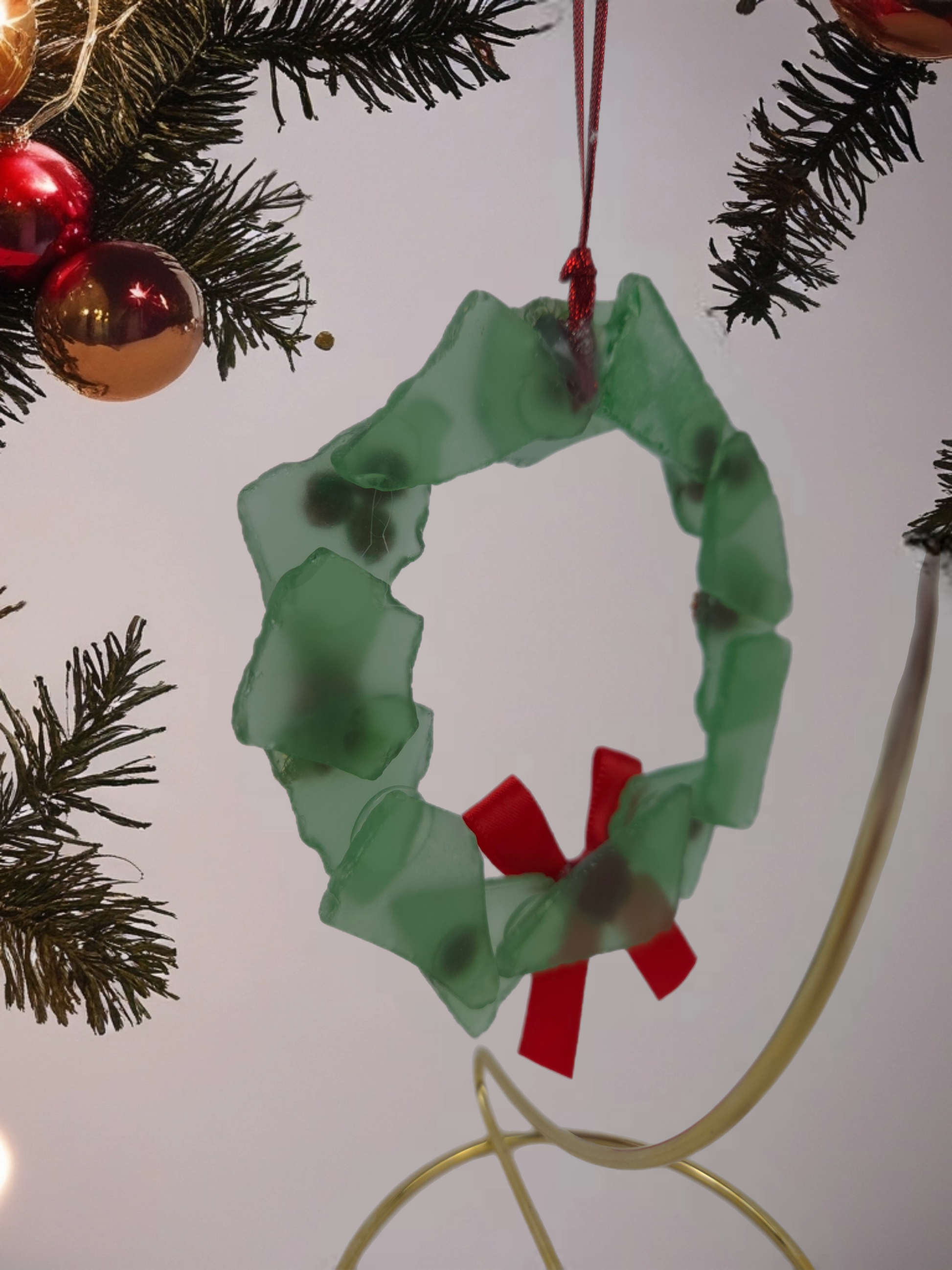 Green wreath ornament with red center on a Christmas tree