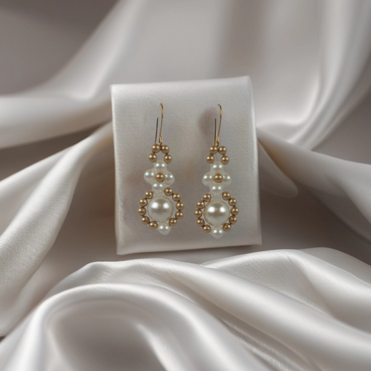 Pair of pearl and gold earrings on a white satin surface