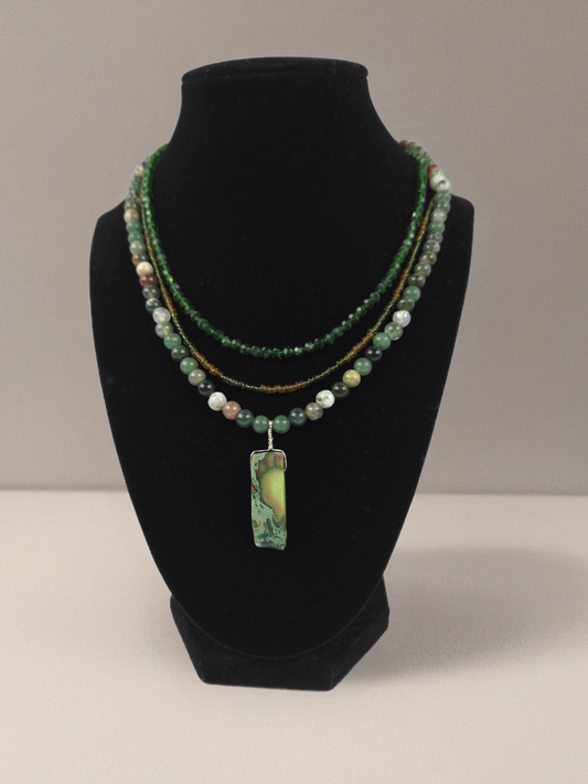 Beaded necklace with a pendant on a black bust against a gray background