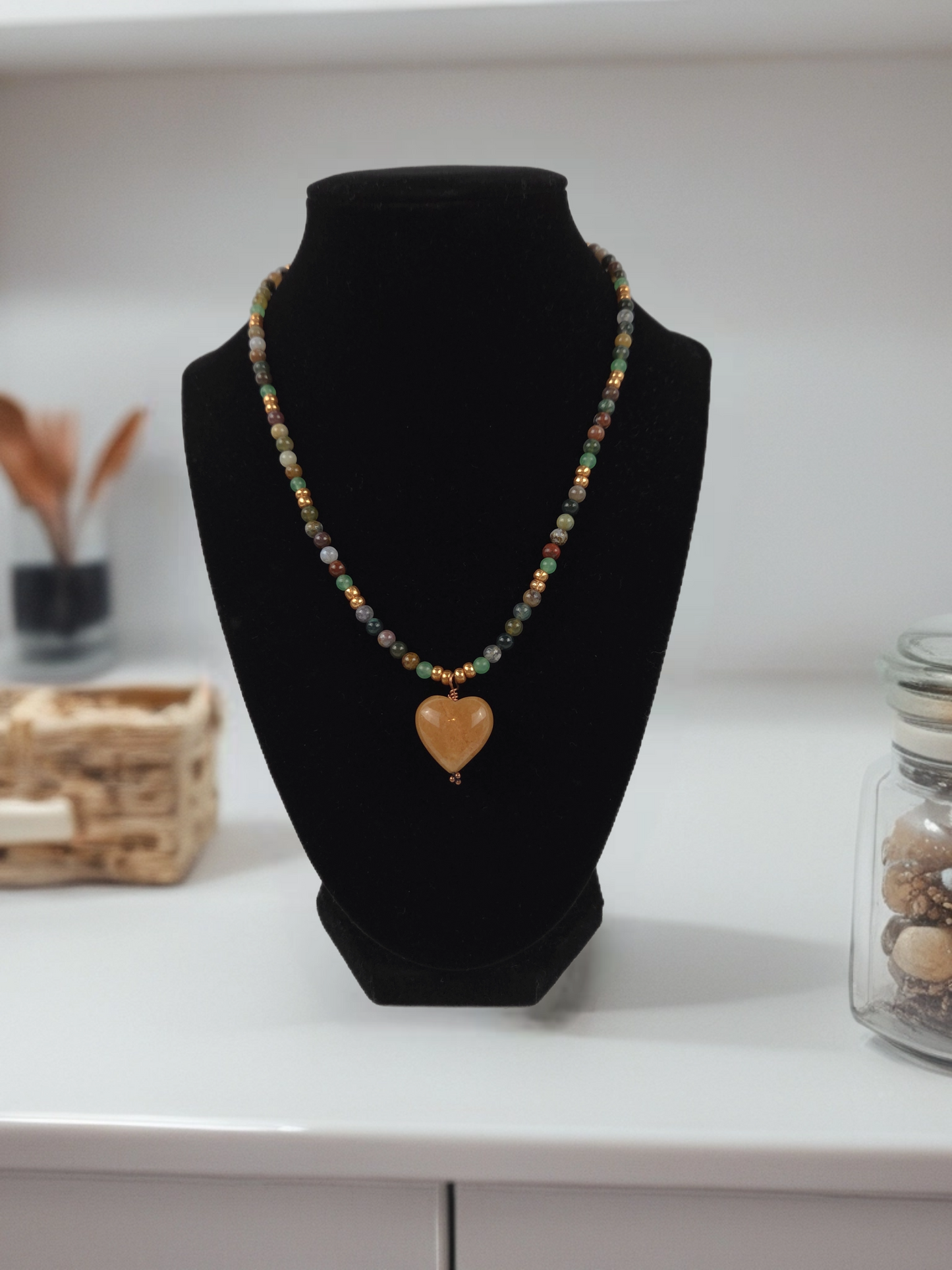 Necklace with a heart-shaped pendant on a black bust against a neutral background