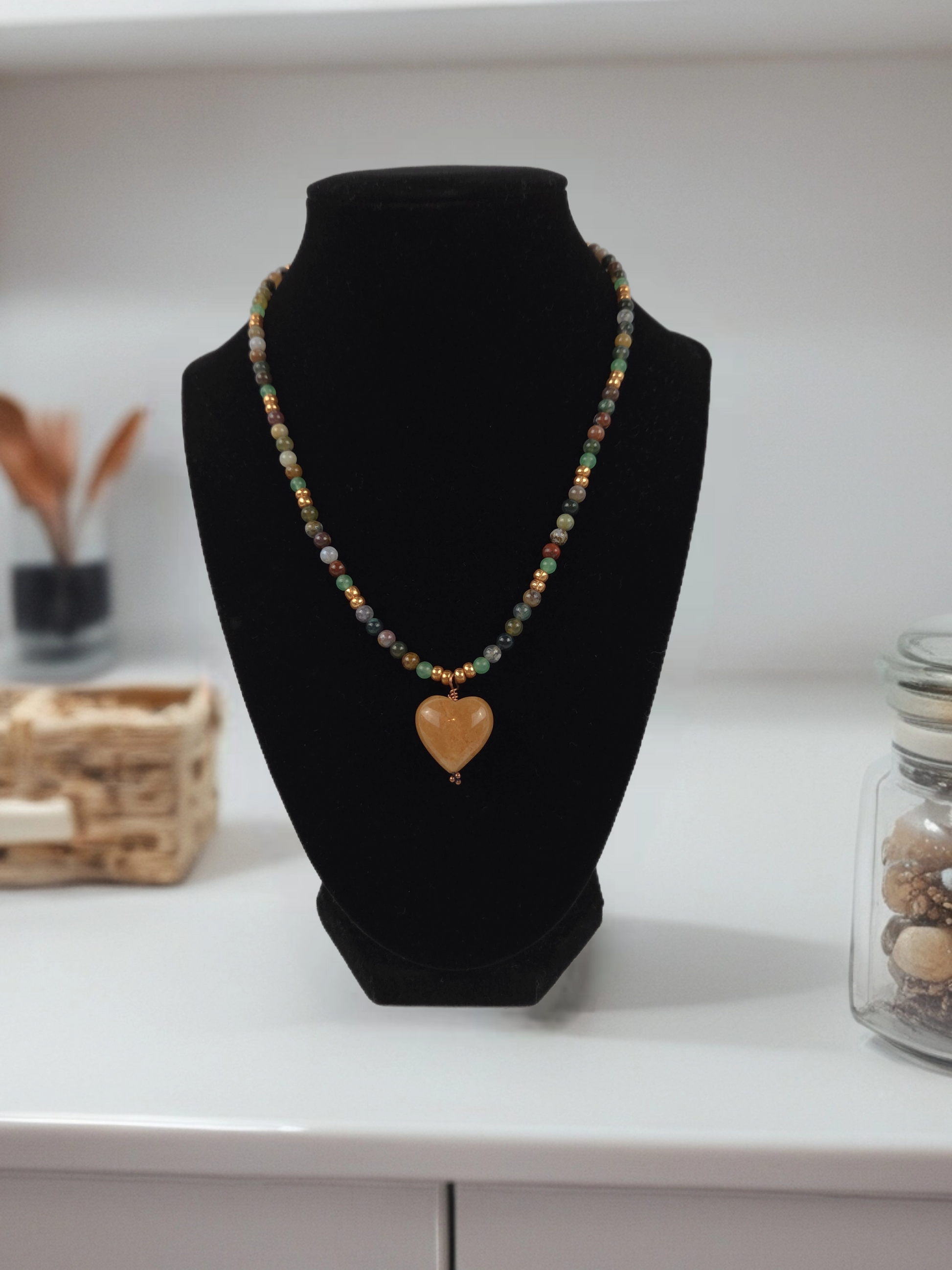 Necklace with a heart-shaped pendant on a black bust against a neutral background