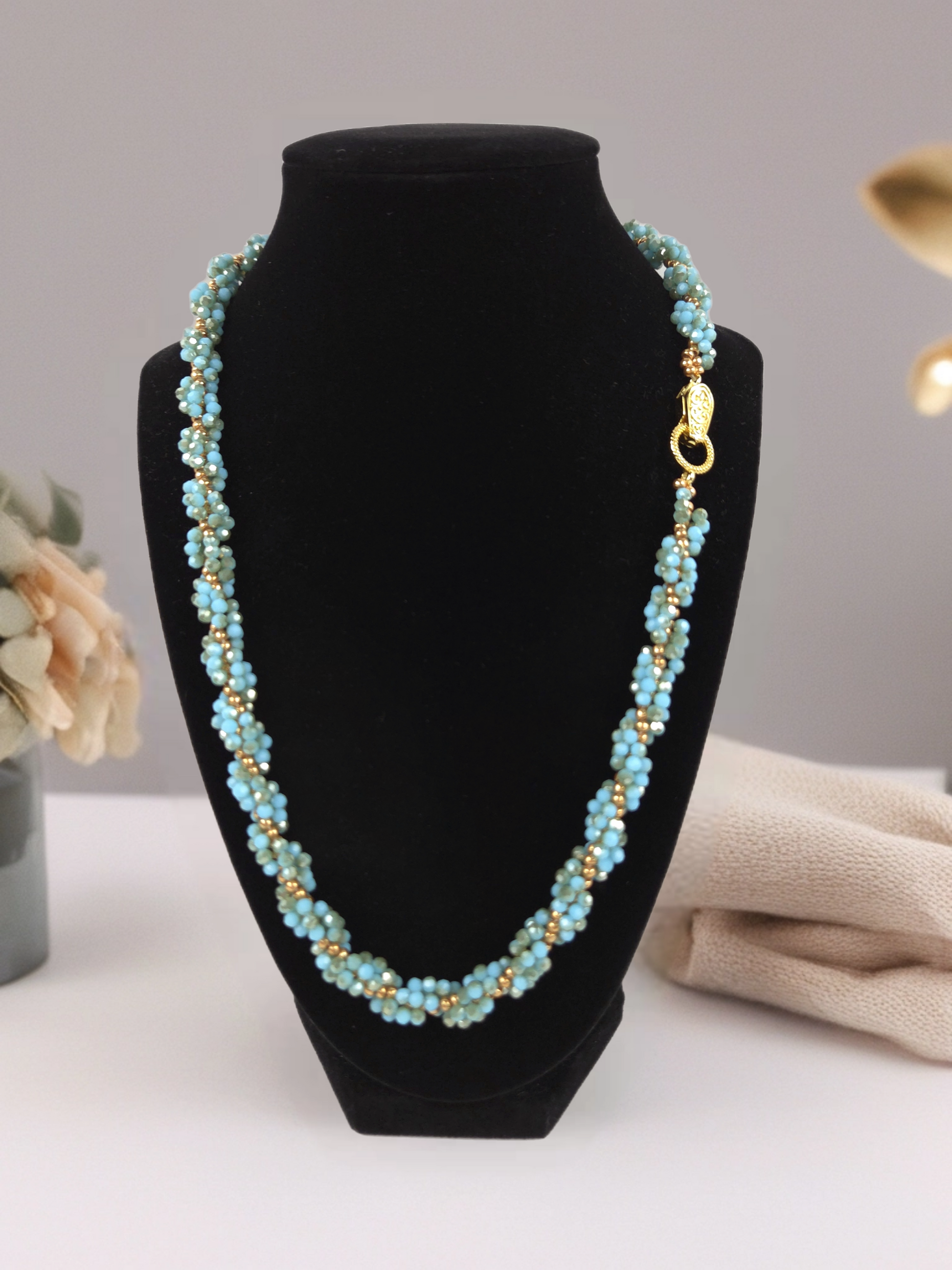 Turquoise beaded necklace on a black bust with a neutral background