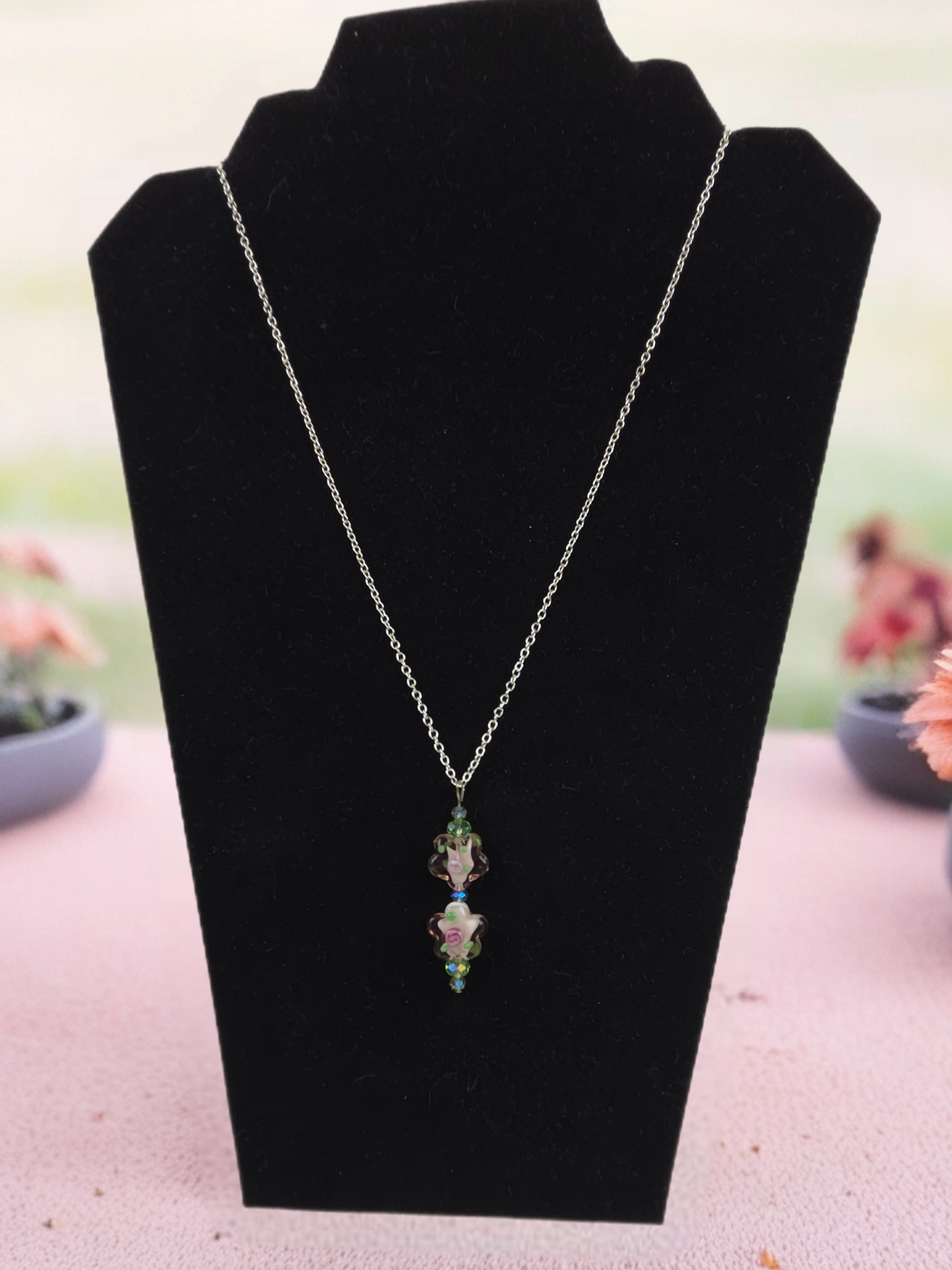 Necklace with a pendant on a black velvet stand with a blurred outdoor background
