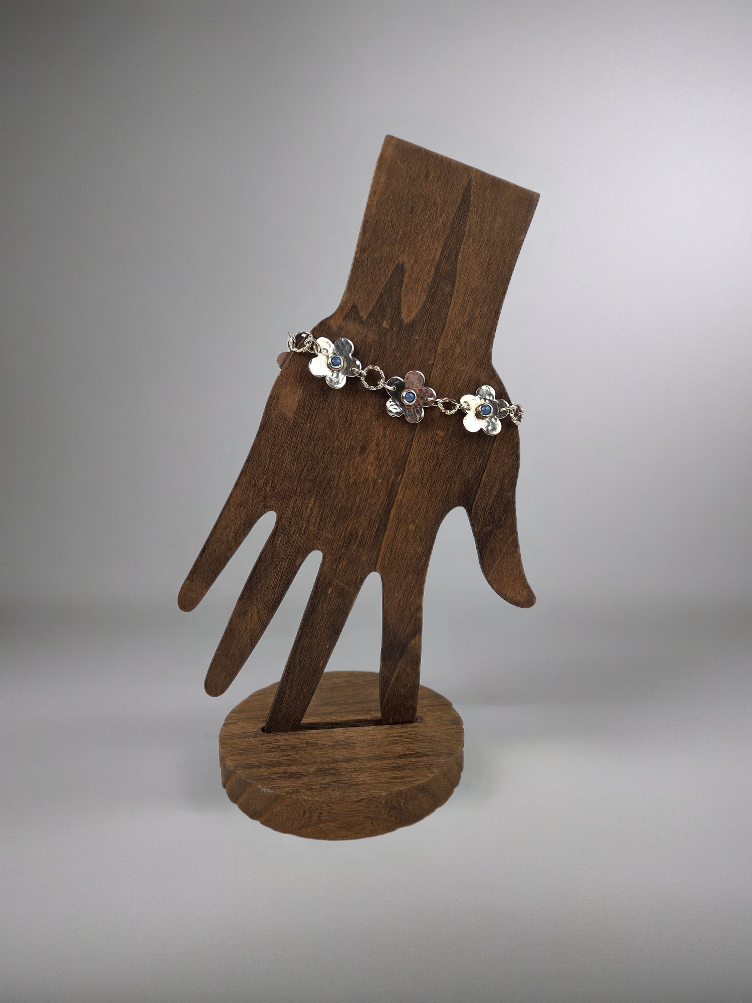 Wooden hand-shaped stand with a floral bracelet on a gray background